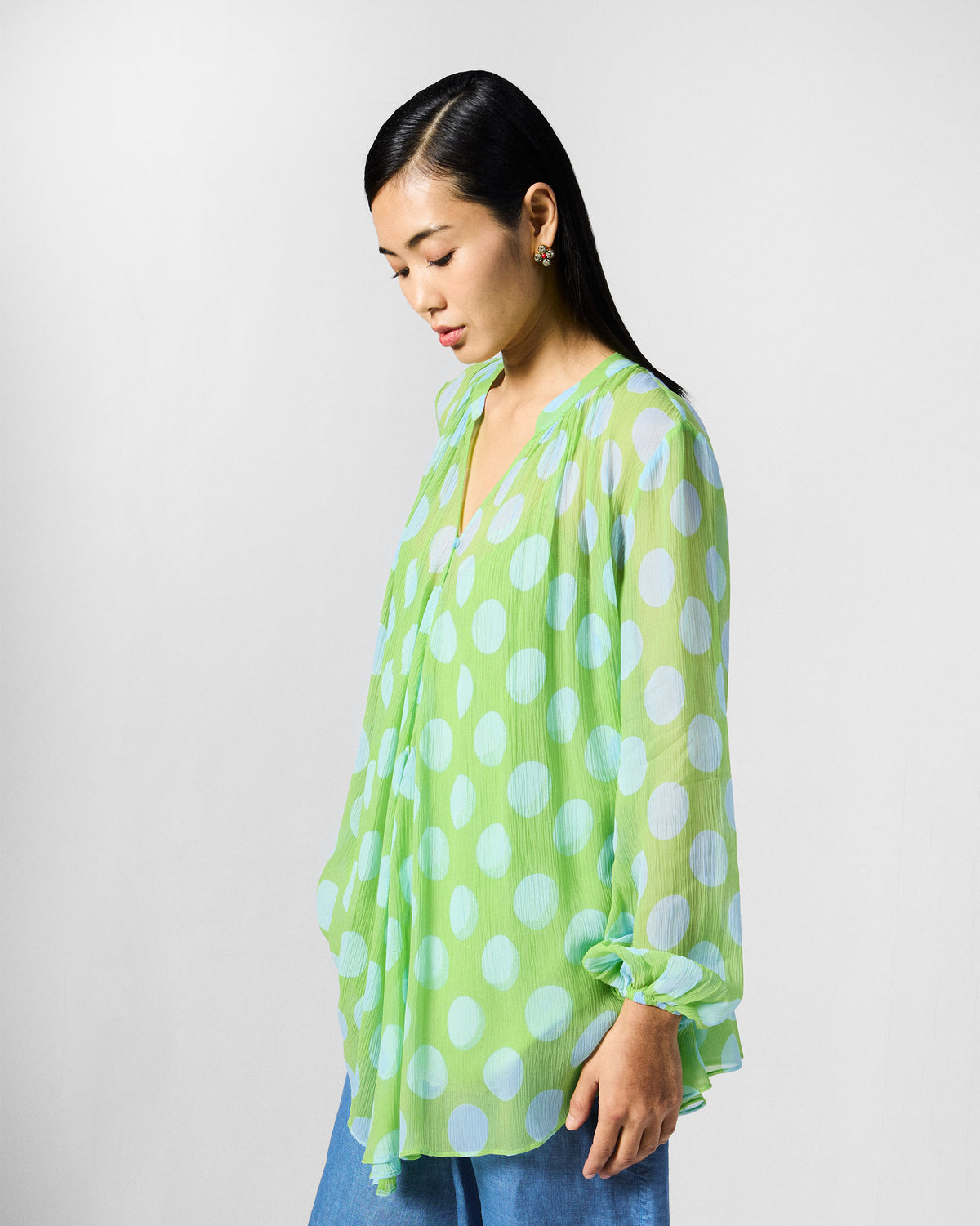 Side view of a green and blue polka-dot Jora top with billowy sleeves.