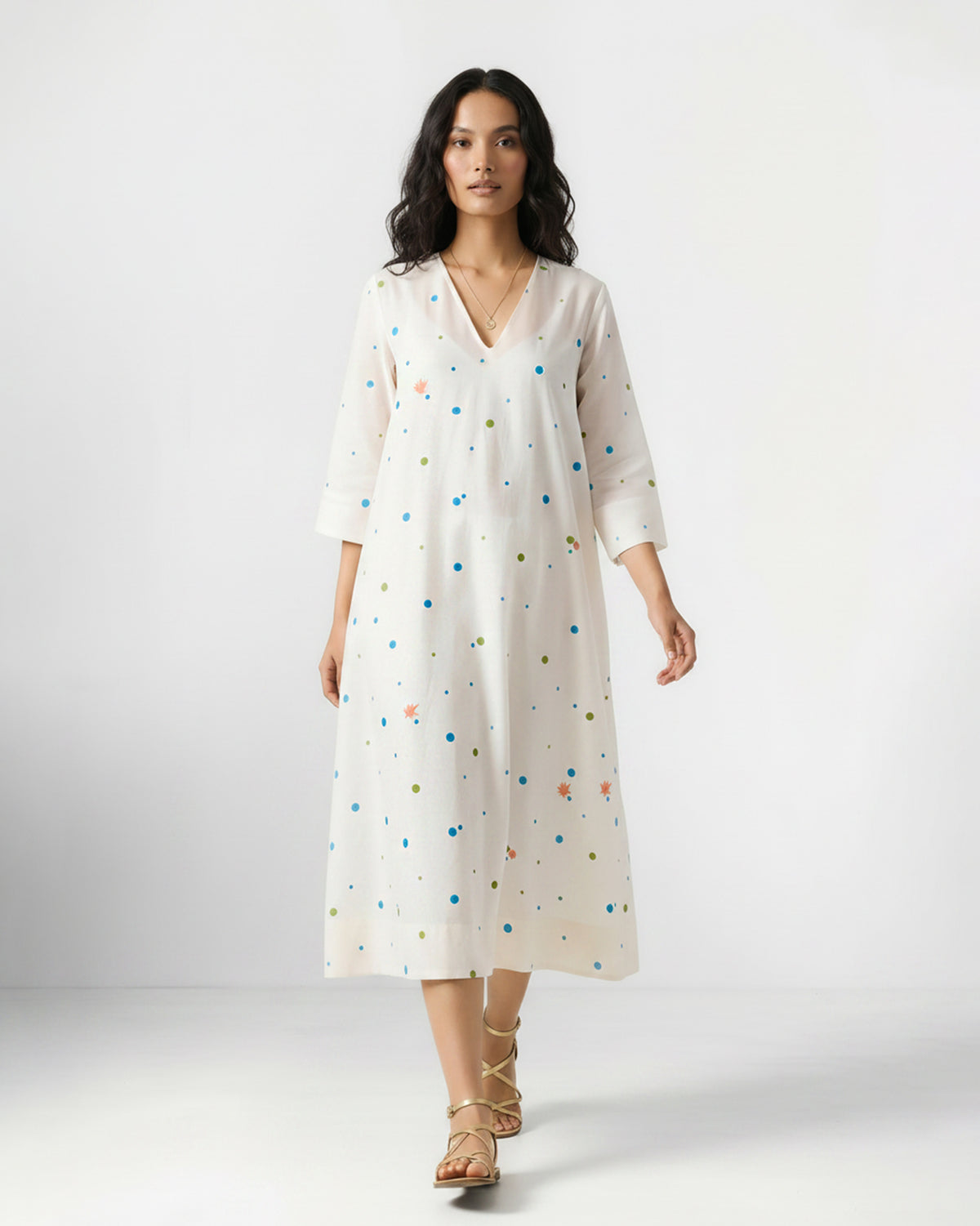 Person wearing an ivory Meadow dress with blue and green dot embroidery.