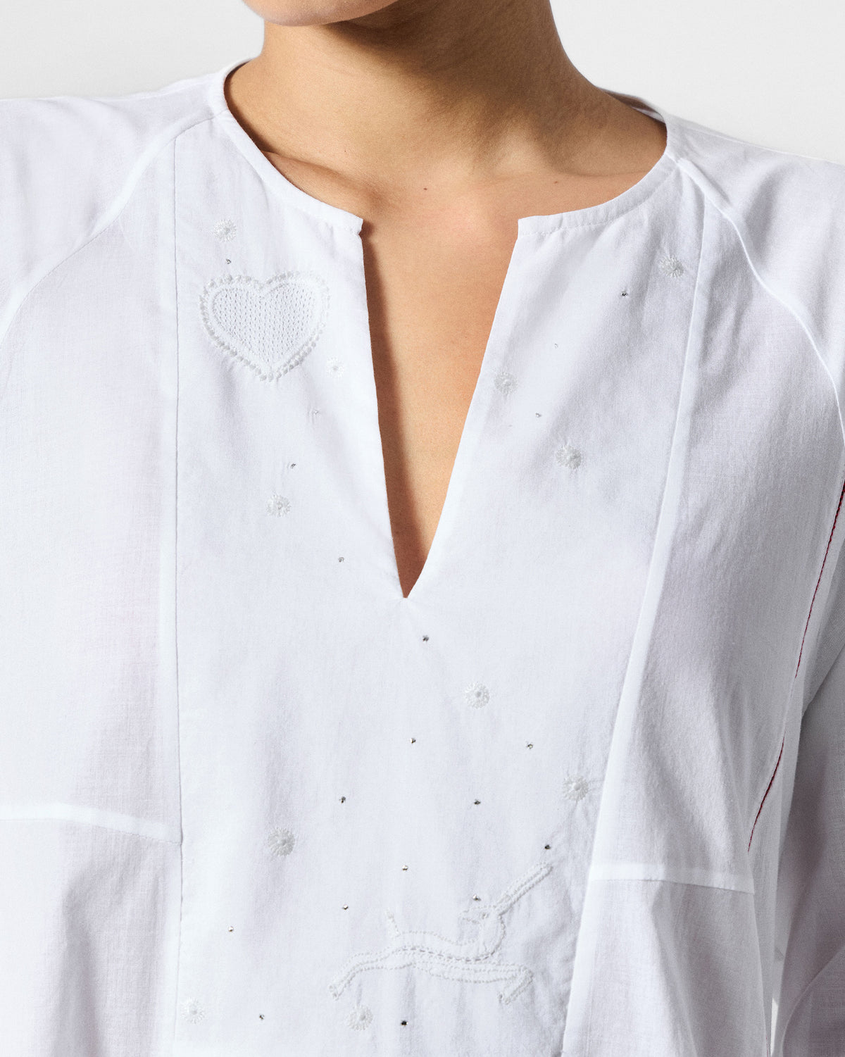 Close-up of white embroidery and a heart motif on a Torsa dress.