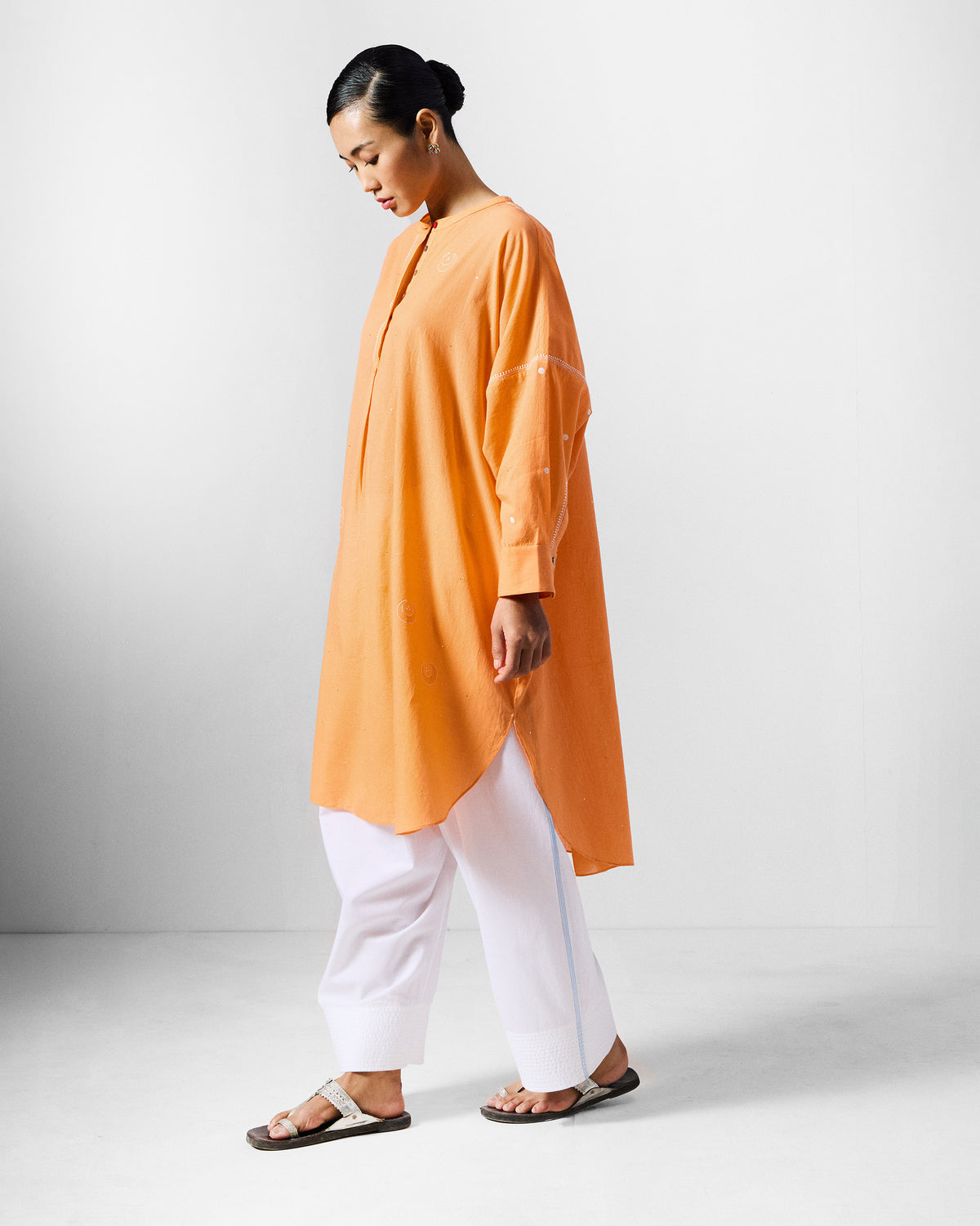 Side view of an orange Lazy Sunday tunic with a longline curved hem.