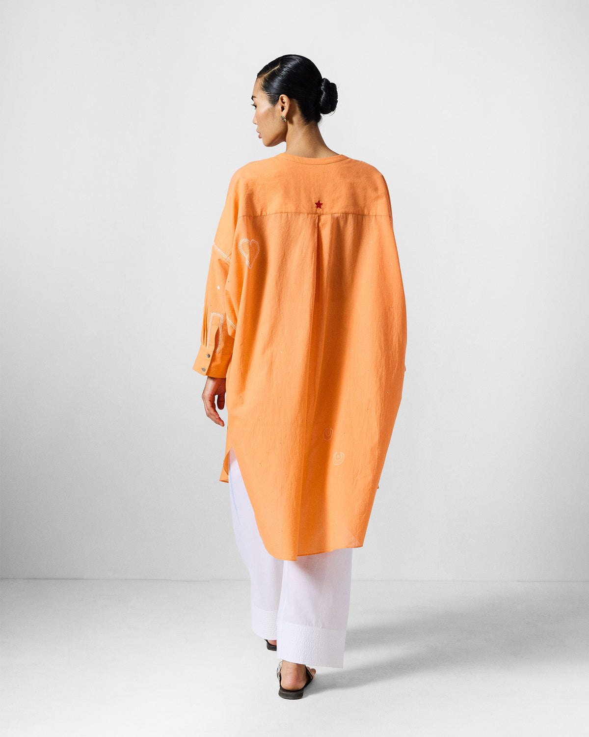 Back of an orange Lazy Sunday tunic with a red star on the yoke.