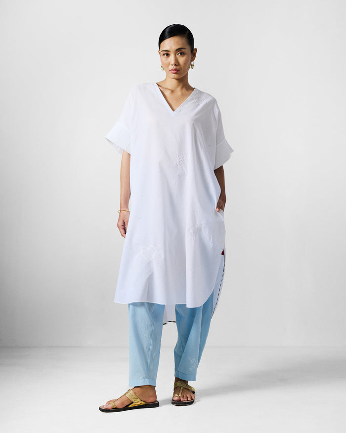 Person wearing a white Calicut kurta with short sleeves and tonal embroidery.
