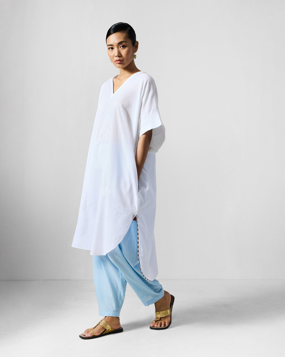 Side view of a white Calicut kurta with a side pocket and high-low hem.