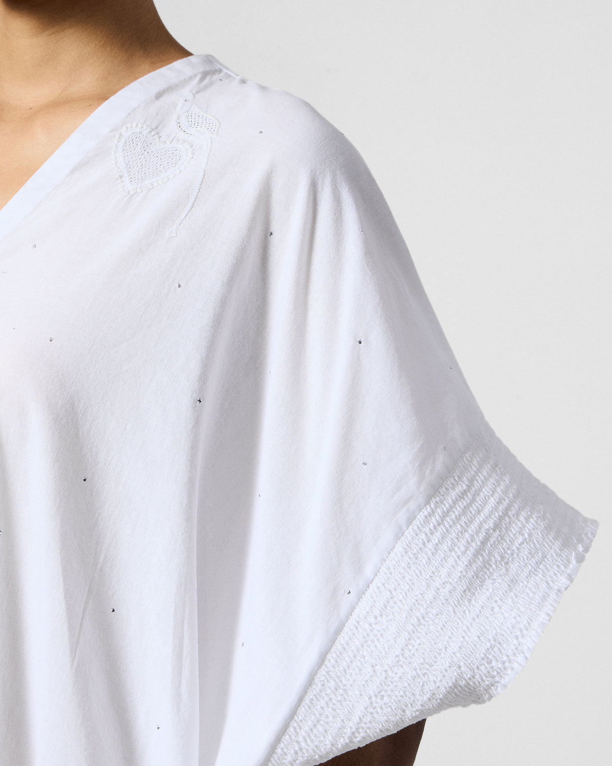 Close-up of white heart embroidery on the shoulder of a Calicut kurta.