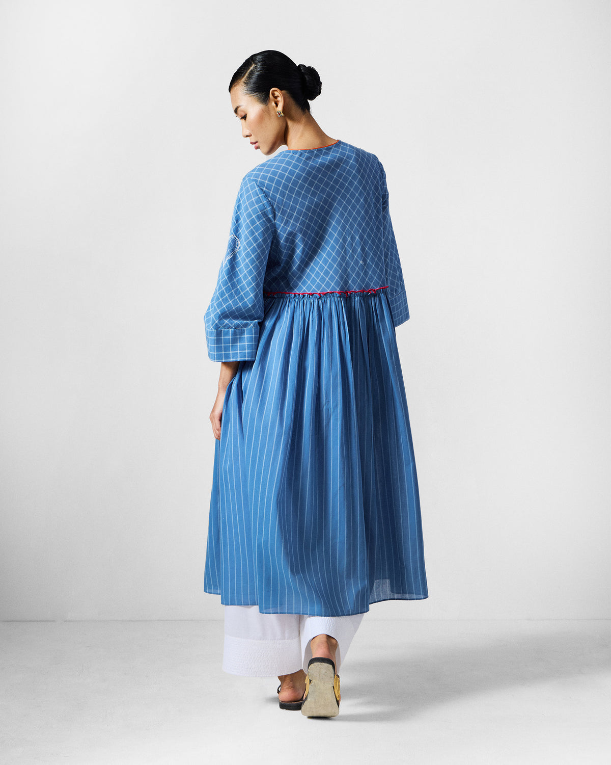 Back of a blue-and-white check Giri kurta with a gathered striped skirt panel.