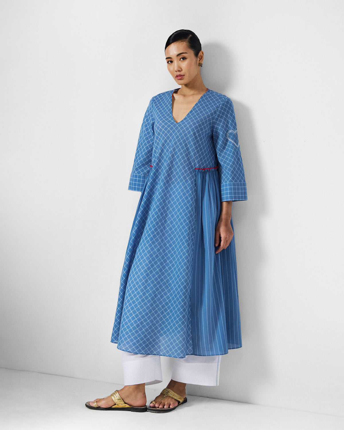 Person wearing a blue-and-white check Giri kurta with a striped side panel.