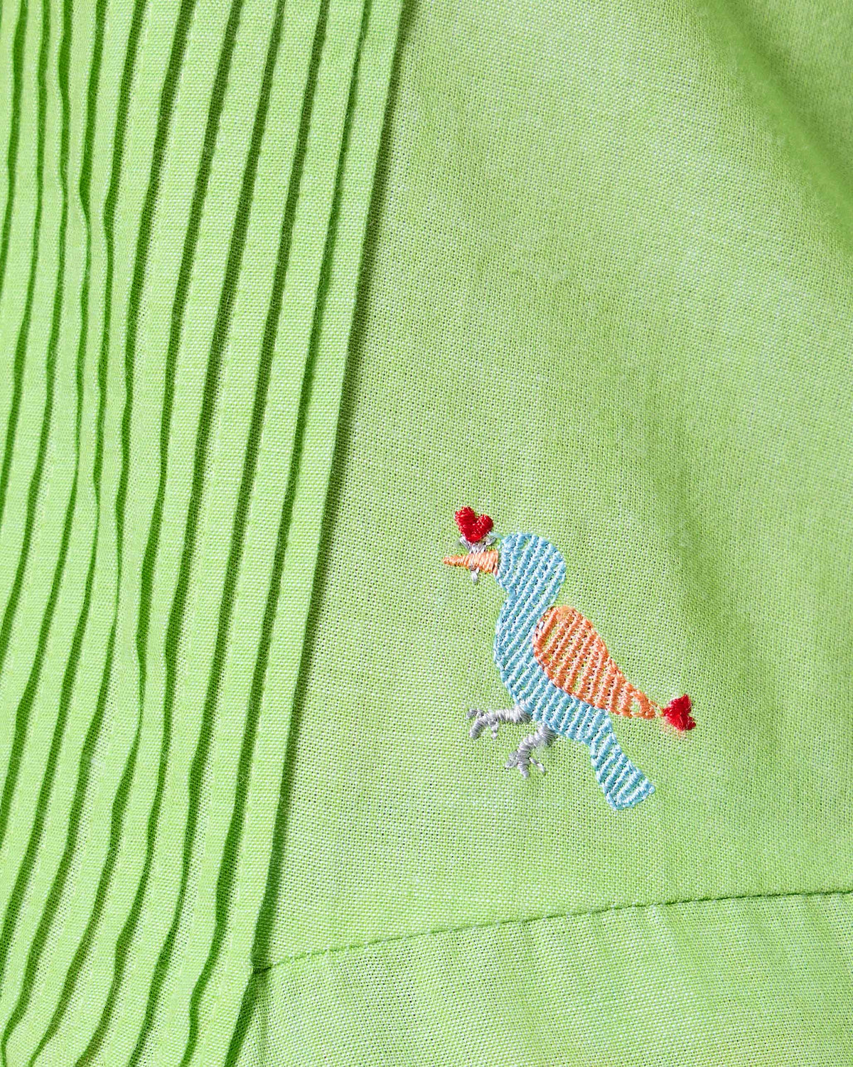 Close-up of a light green Yara dress showing a small embroidered bird on the bodice.
