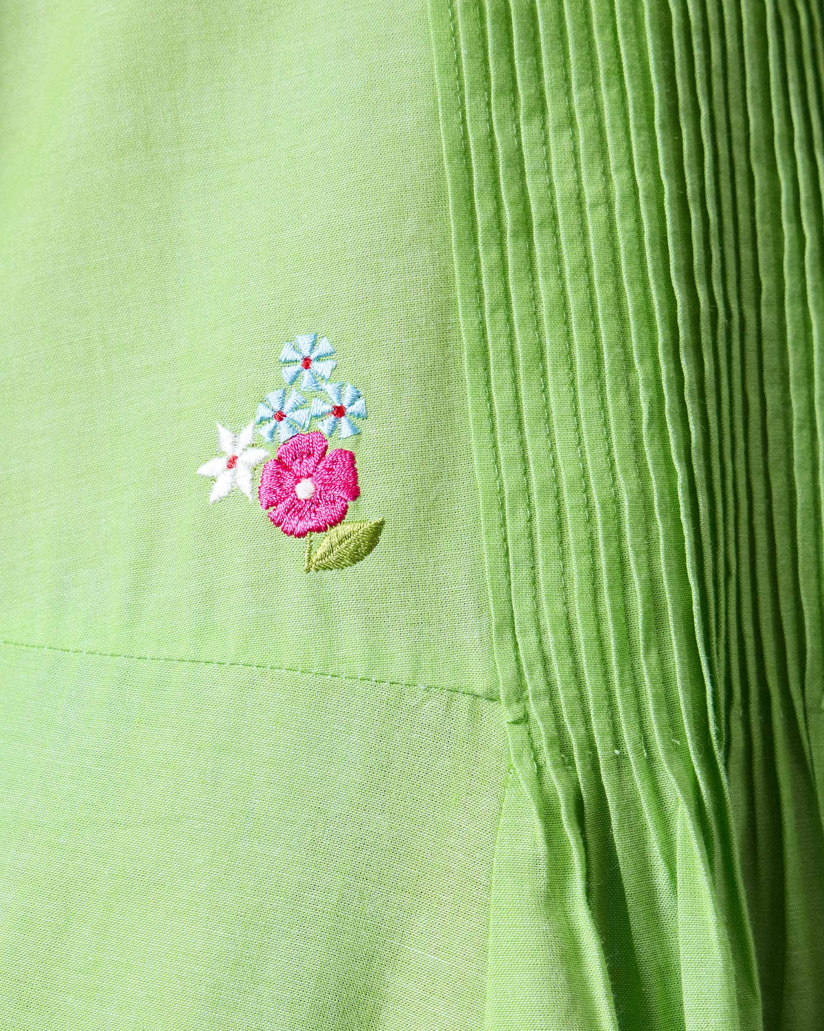 Close-up of a light green Yara dress showing small embroidered flowers on the bodice.