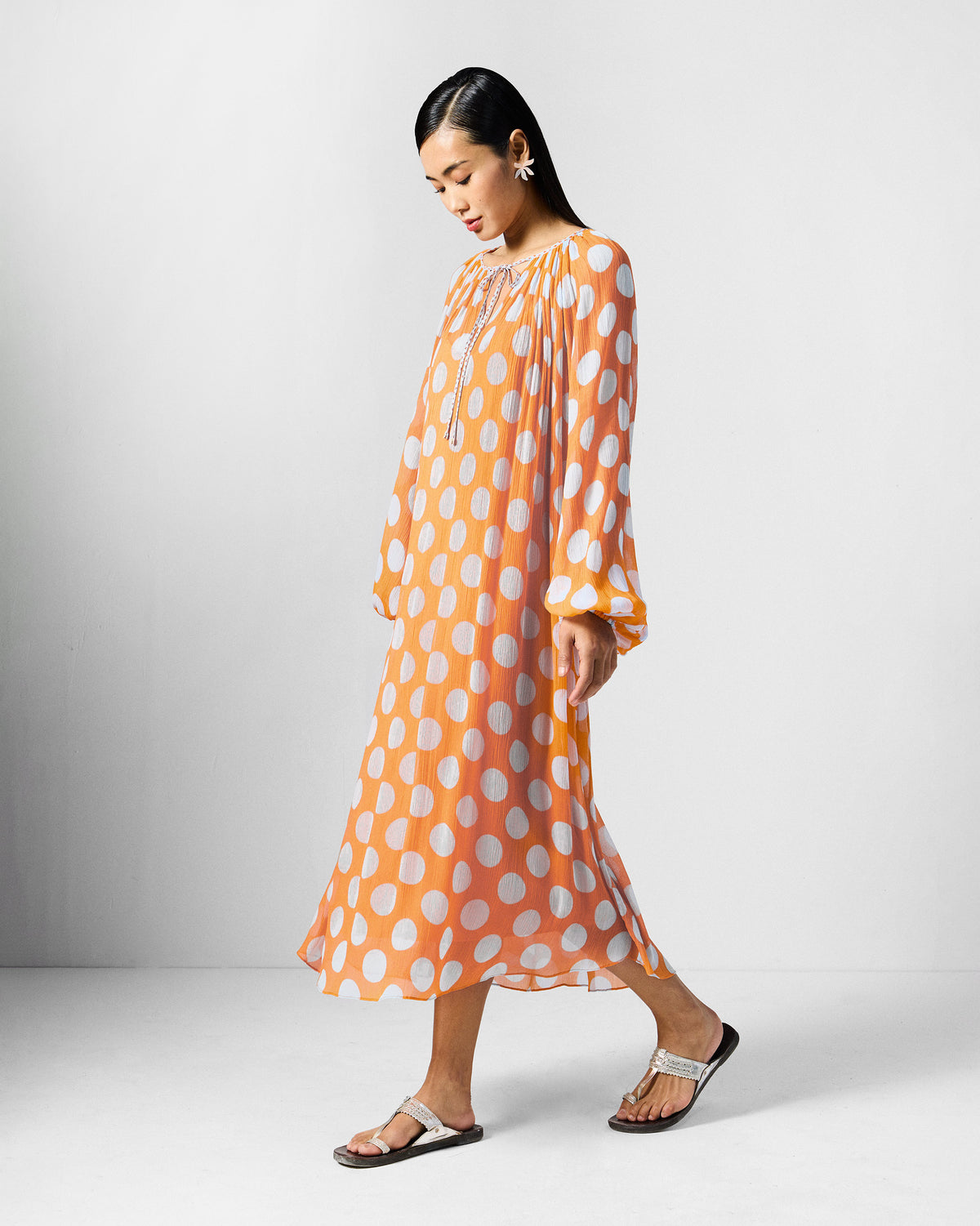 Side view of an orange Sara kaftan with white dots and gathered sleeves.