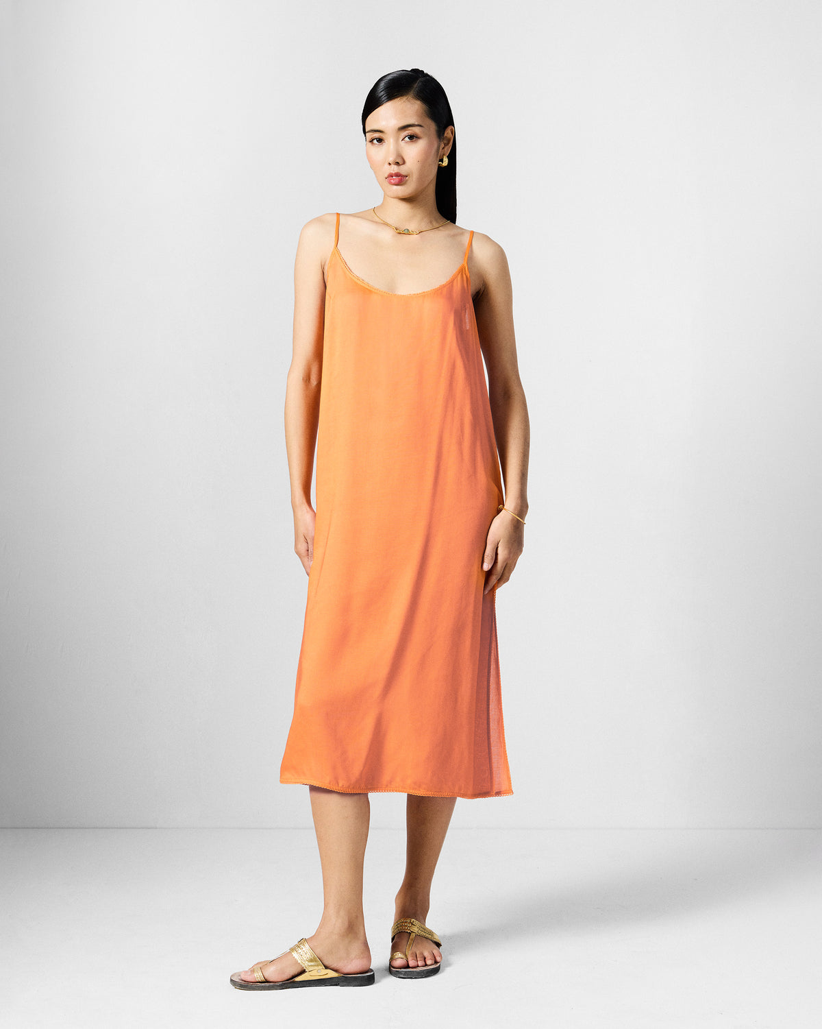 Person wearing a solid orange sleeveless midi slip dress.