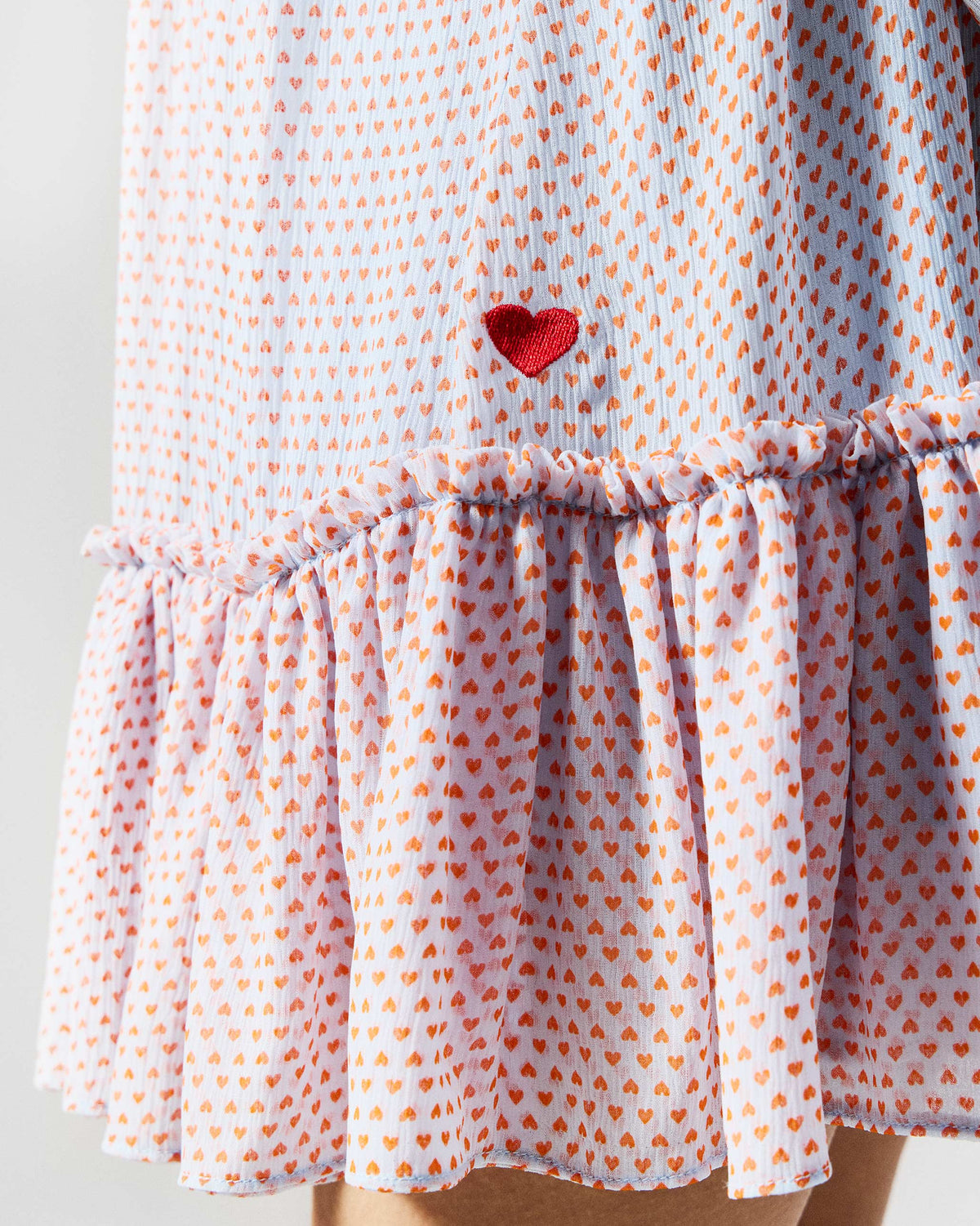 Close-up of a blue and orange printed Siya dress with a red heart above the ruffle.