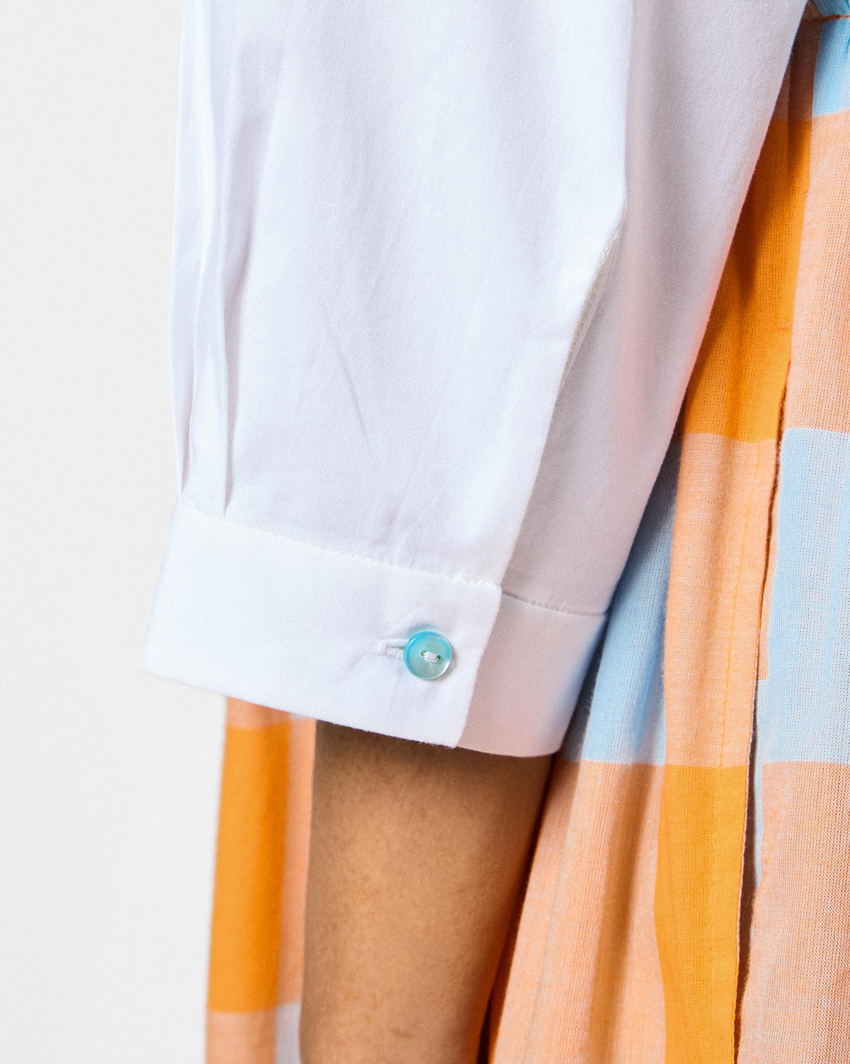 Close-up of a white dress sleeve with a pearlescent button.