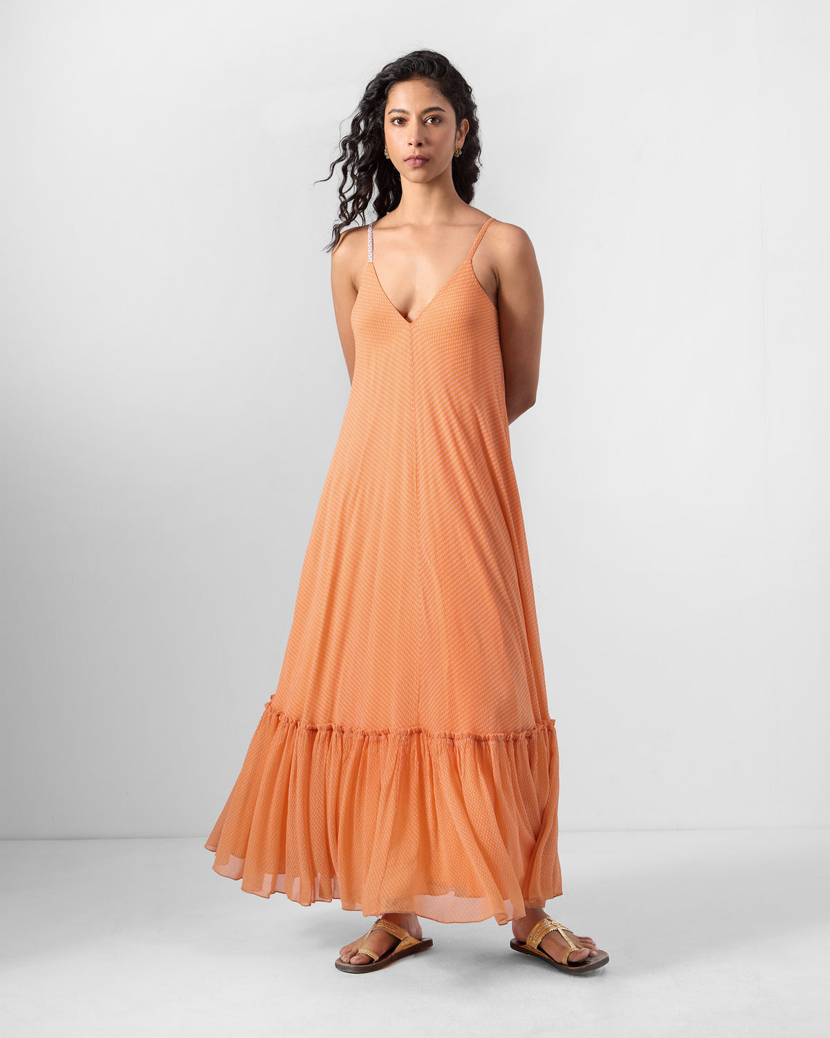 Person wearing an orange Luma maxi dress with thin straps.