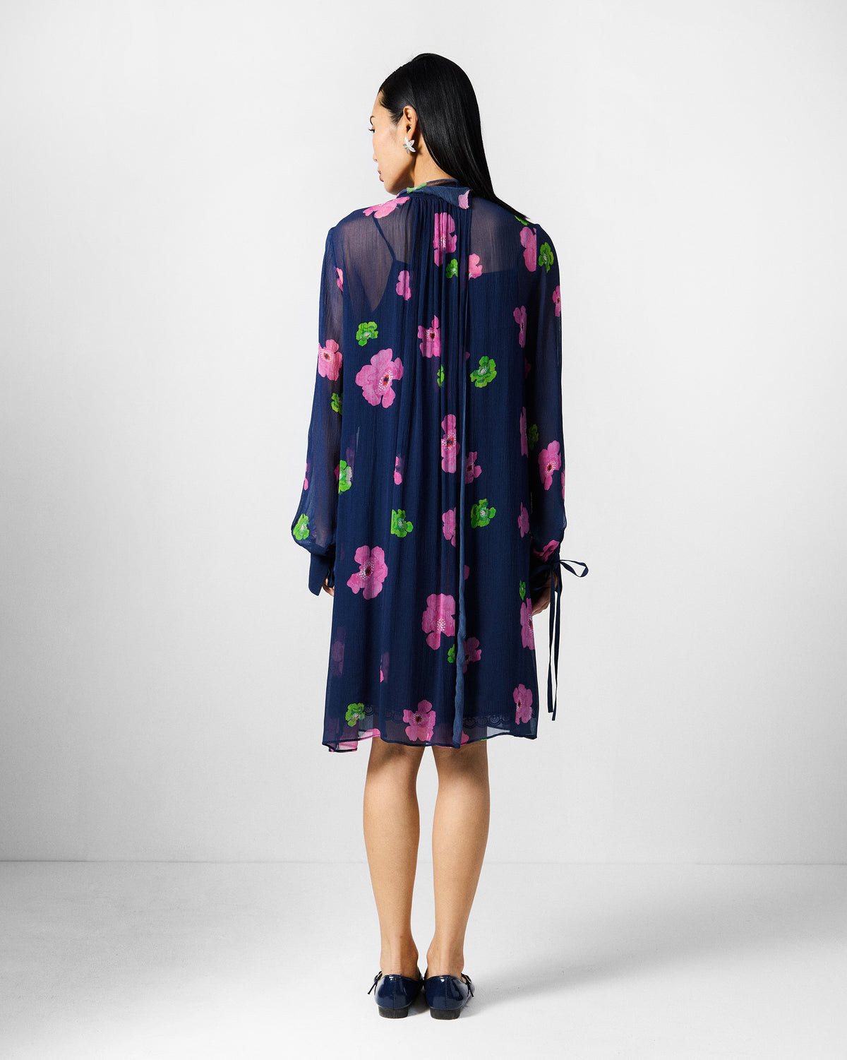 Back of a navy floral Raya dress with gathered centre pleats.