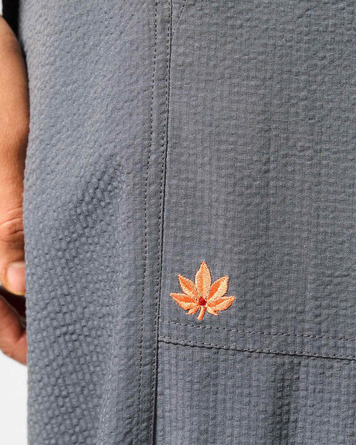 Close-up of charcoal joggers with a small orange leaf embroidery.