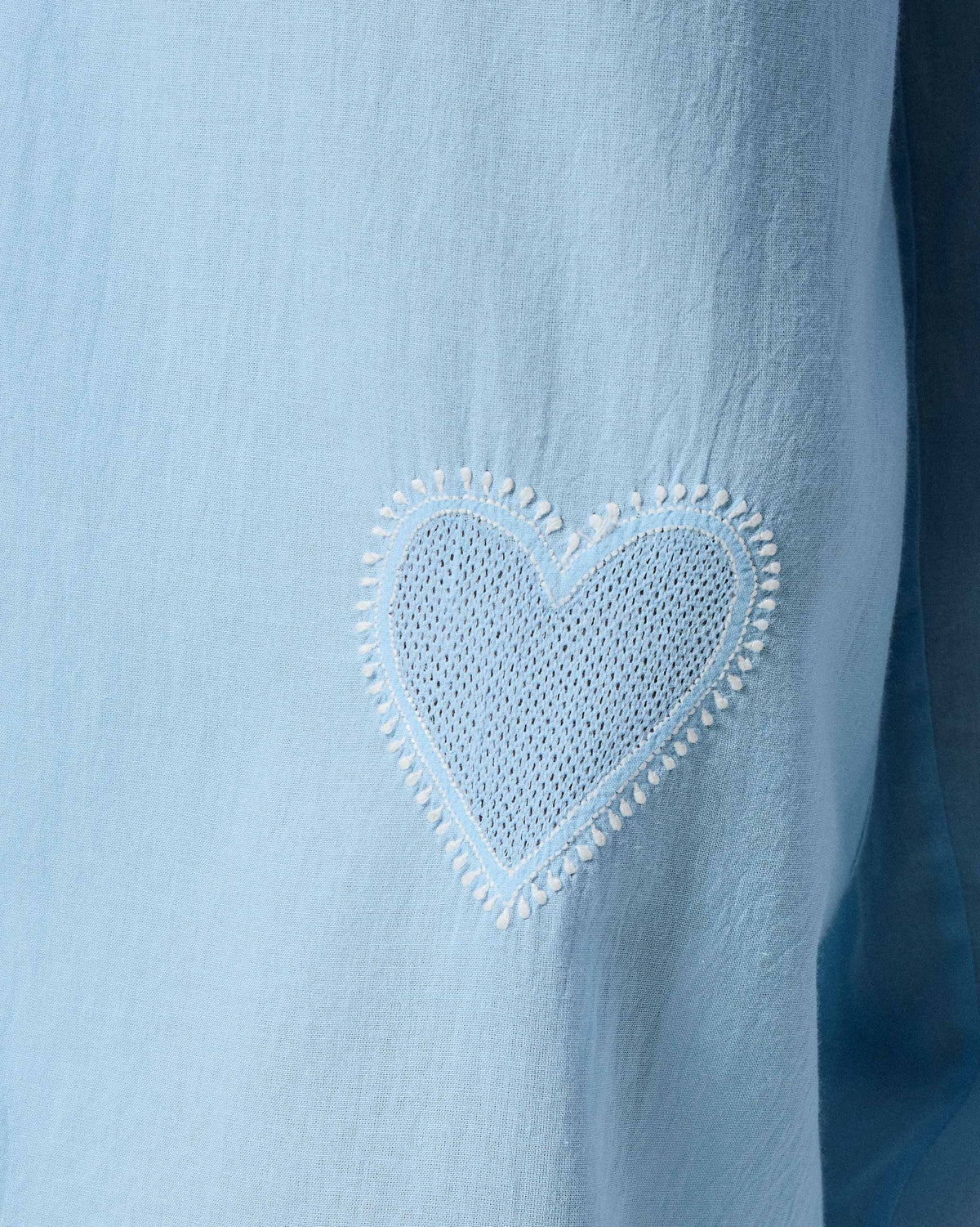 Close-up of a white mesh heart embroidered on ice blue Aaira Pants.