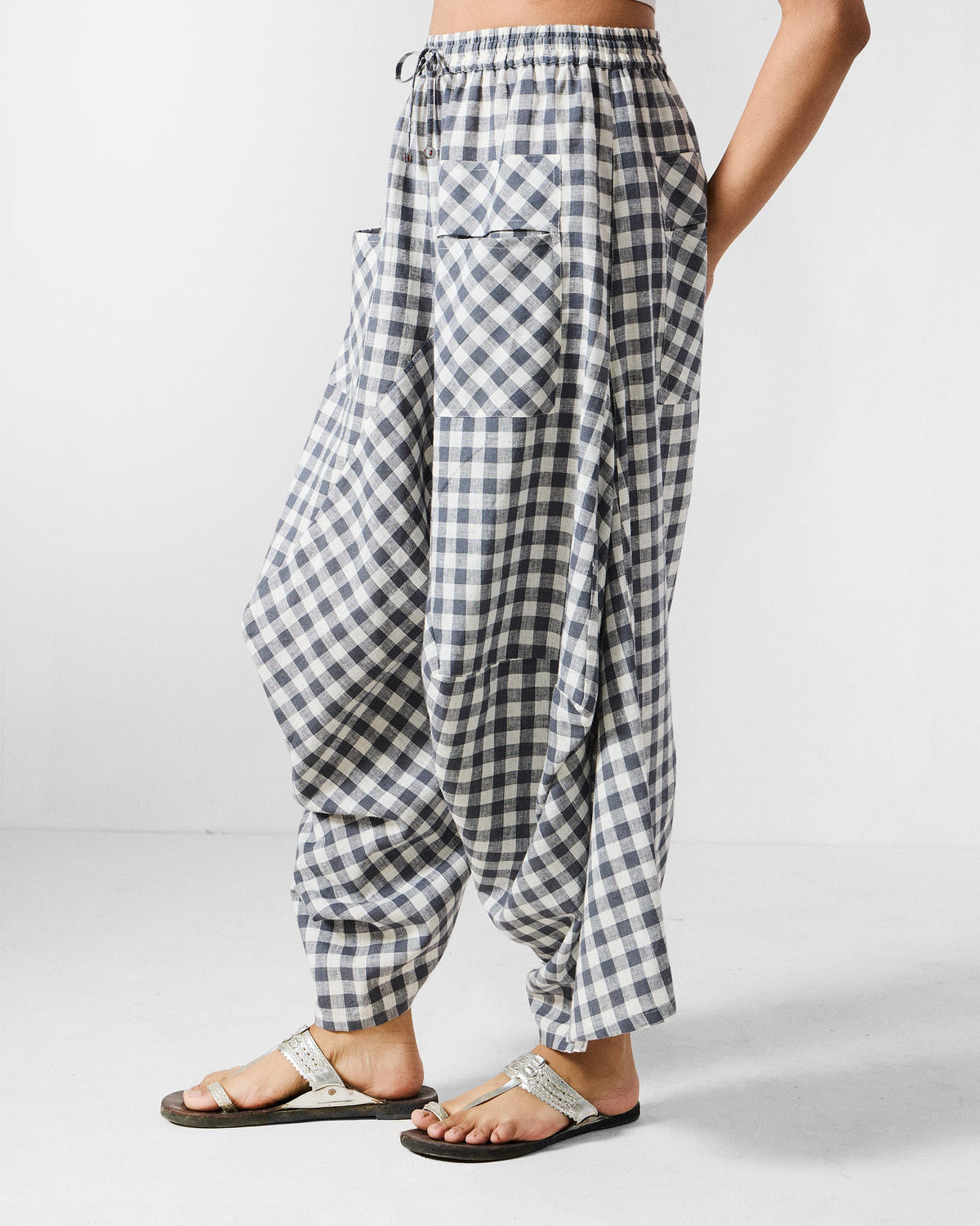 Side view of grey and white checked Yoka trousers showing the draped silhouette.