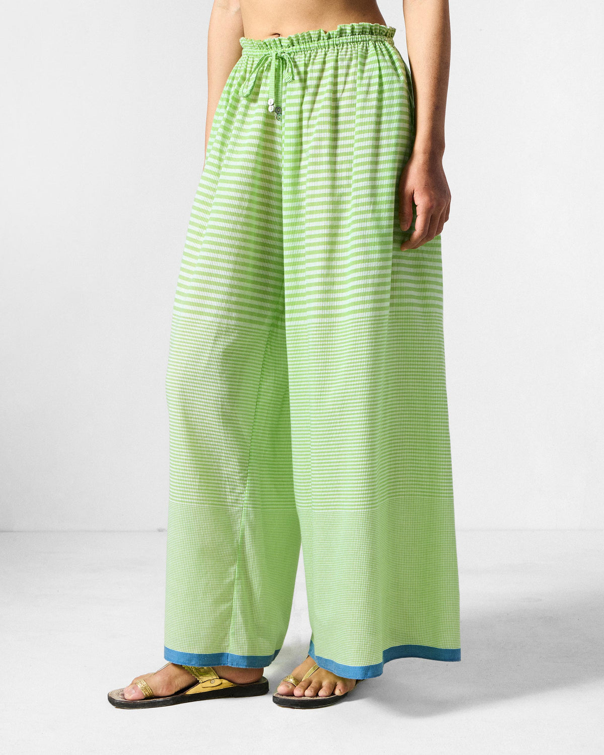 Side view of light green and white check Paperbag Pants with a wide-leg fall.