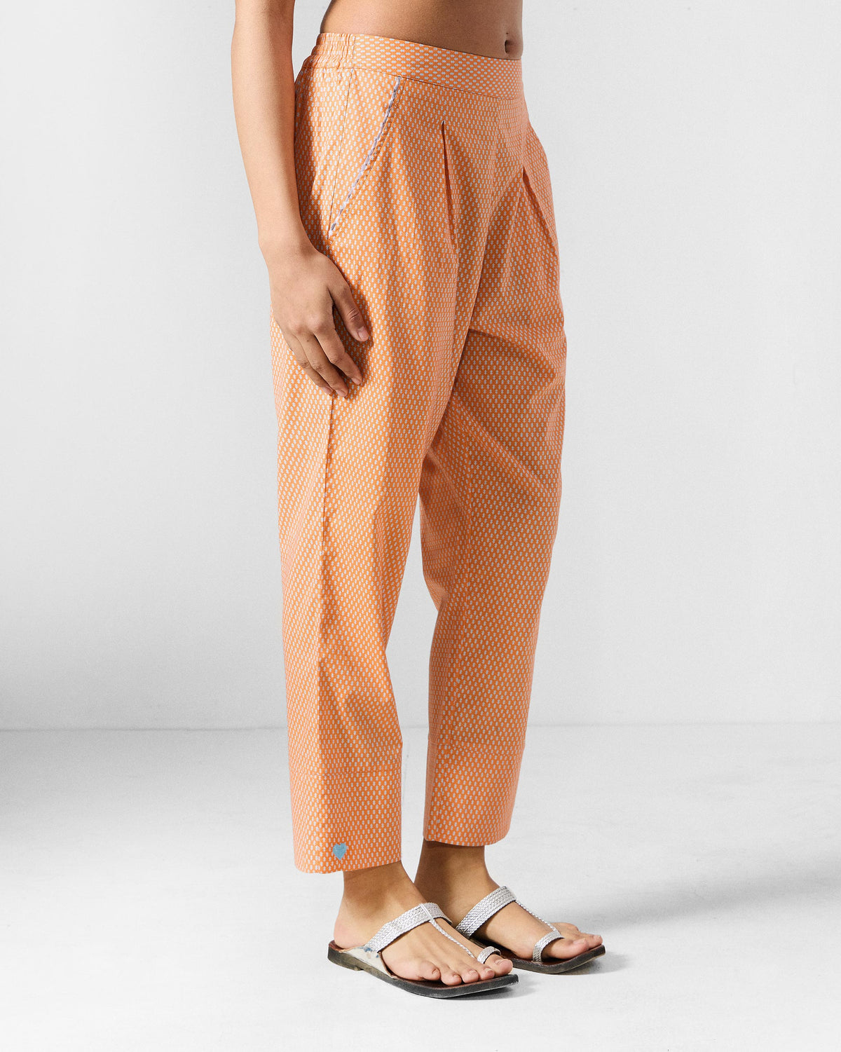 Side view of orange printed Perch pants worn by a person.