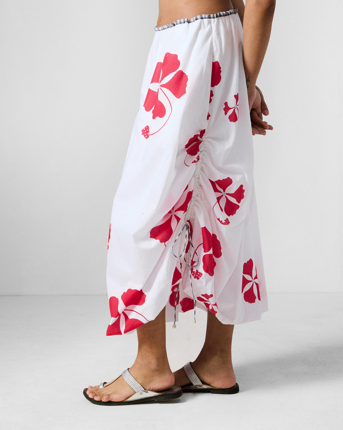 Side view of a white Billow Skirt with red florals and a ruched drawstring.