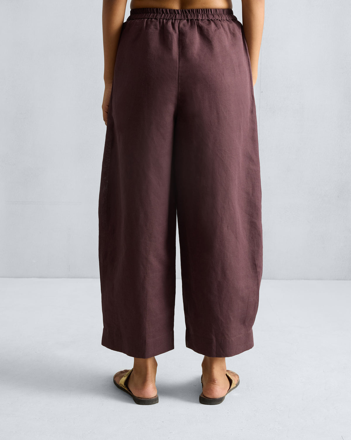 Back of chocolate plum Serene pants with an elastic waistband and cropped legs.