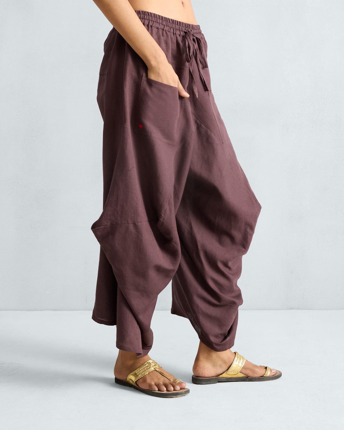 Side view of chocolate plum Yoka Trousers with deep pockets.