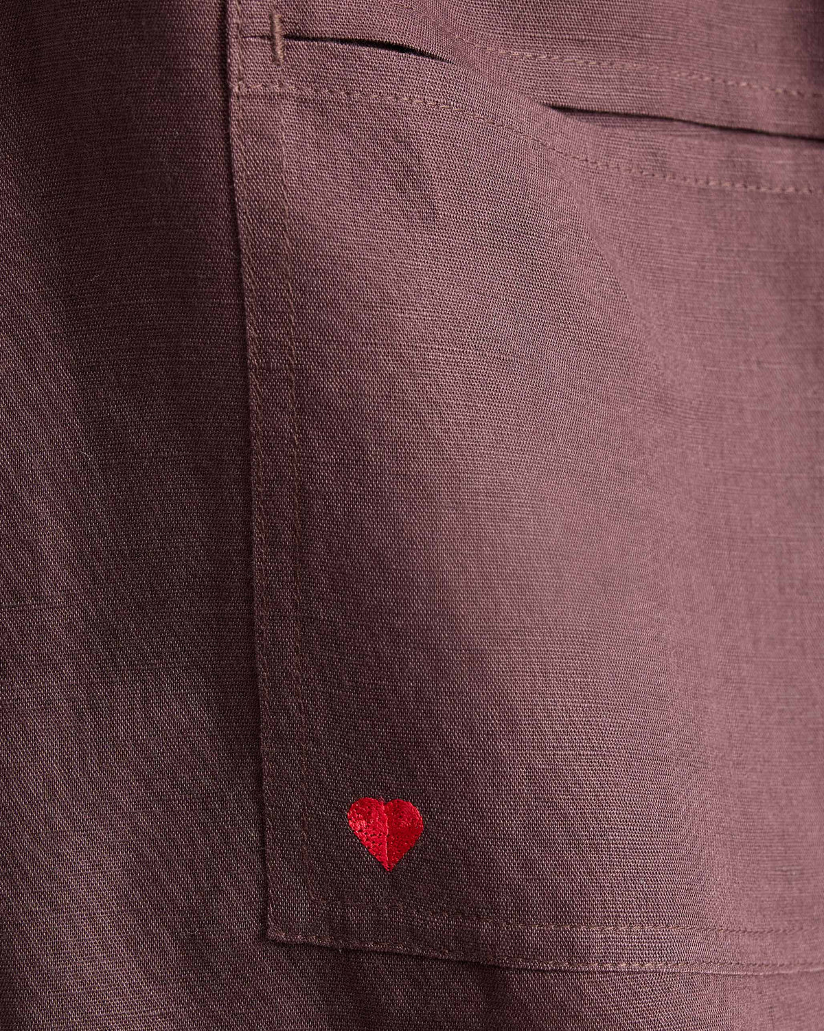 Close-up of a red heart on the pocket of chocolate plum Yoka Trousers.