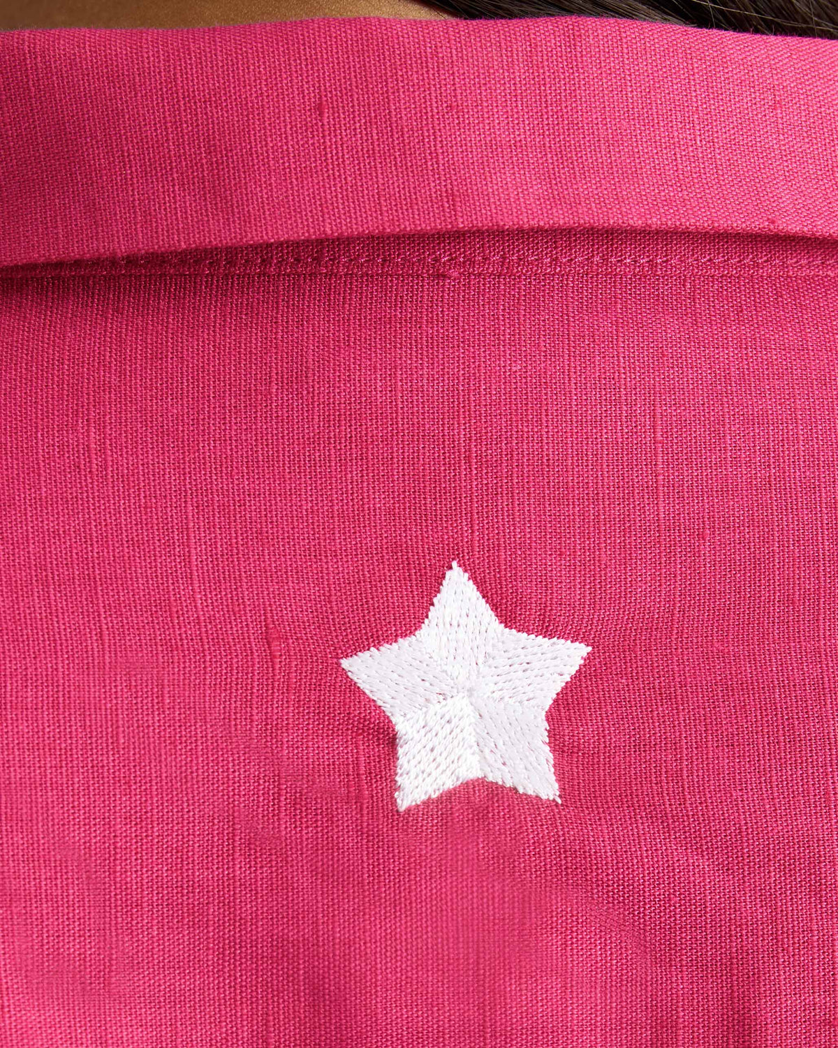 Close-up of a white star on a fuchsia Drop Armhole Shirt.