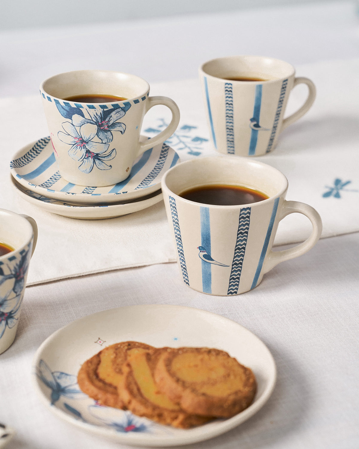 River Tiger espresso mugs filled with coffee on blue-striped saucers.