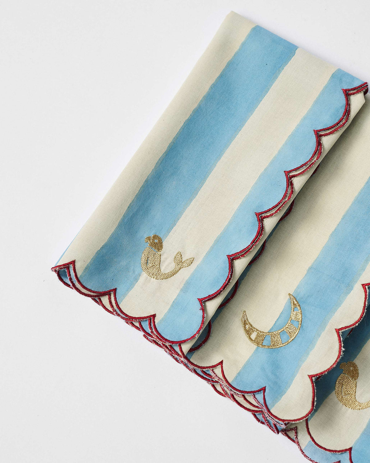 Close-up of gold bird and crescent embroidery on blue-and-cream striped napkins.
