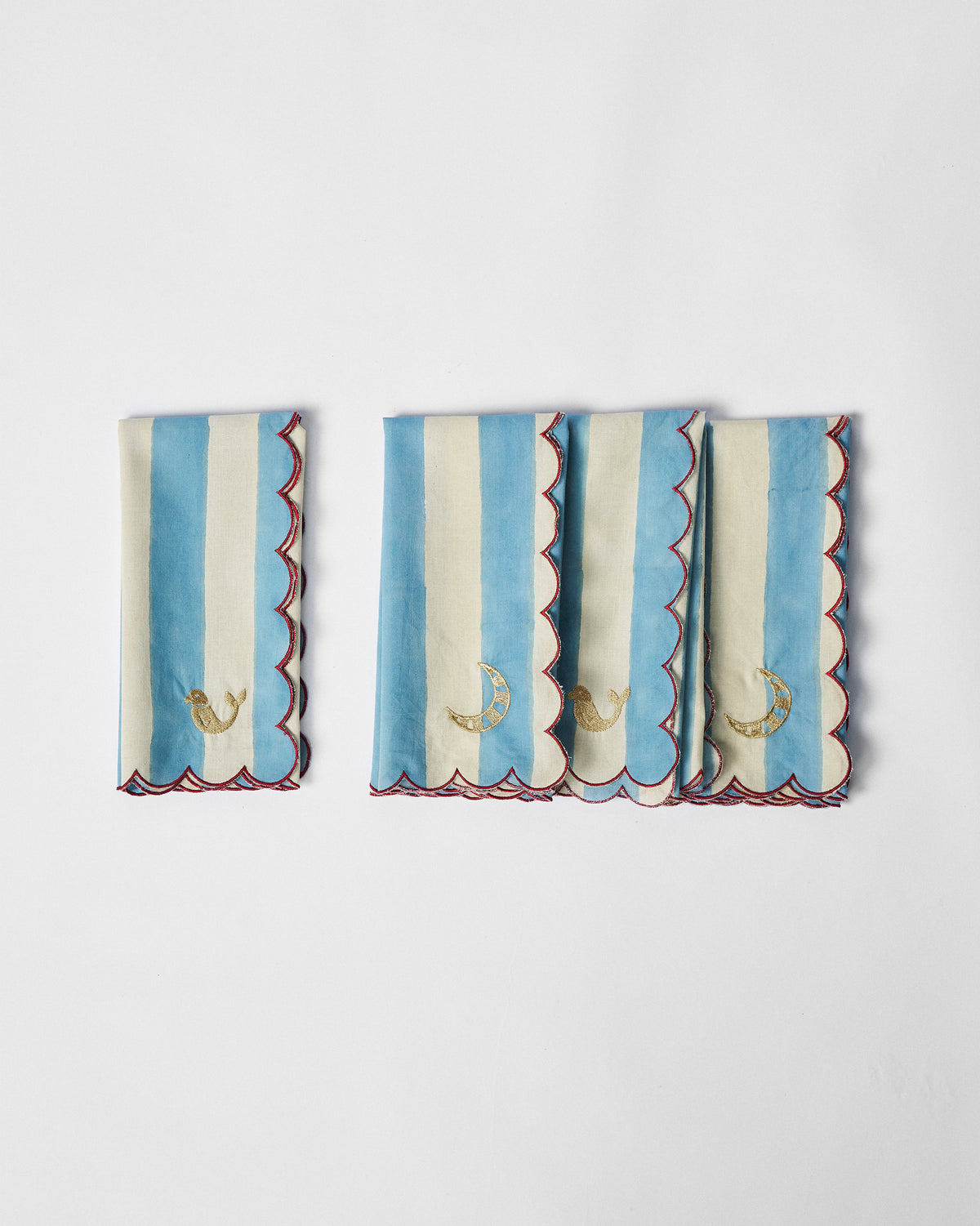 Set of four blue-and-cream striped napkins with red scallops and gold motifs.