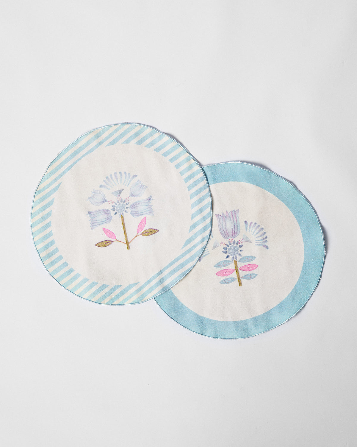 Two Lotus Placemats overlapping, one with a striped and one with a solid blue border.