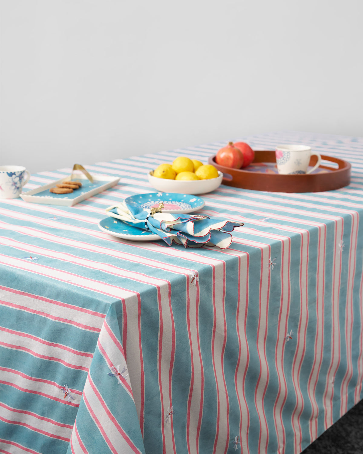 Parijat table cover in blue and pink stripes laid on a table.