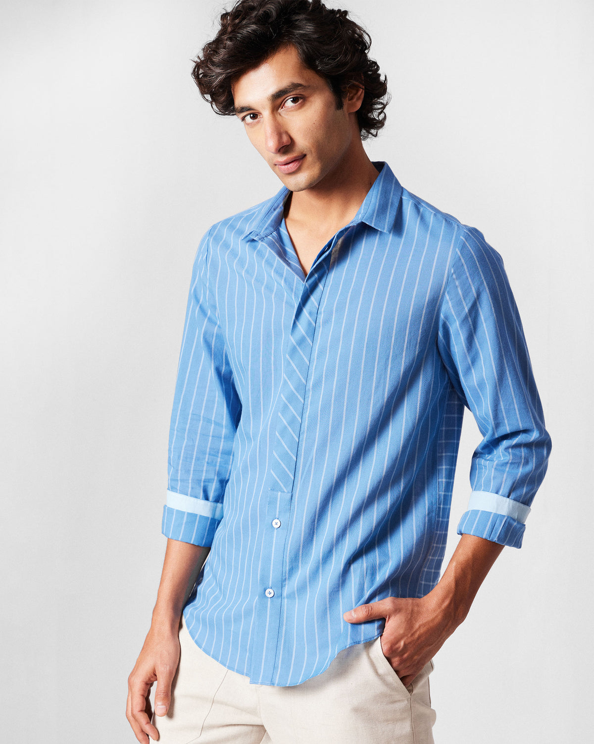 Person wearing a riverside blue Bias Placket shirt with thin white stripes.