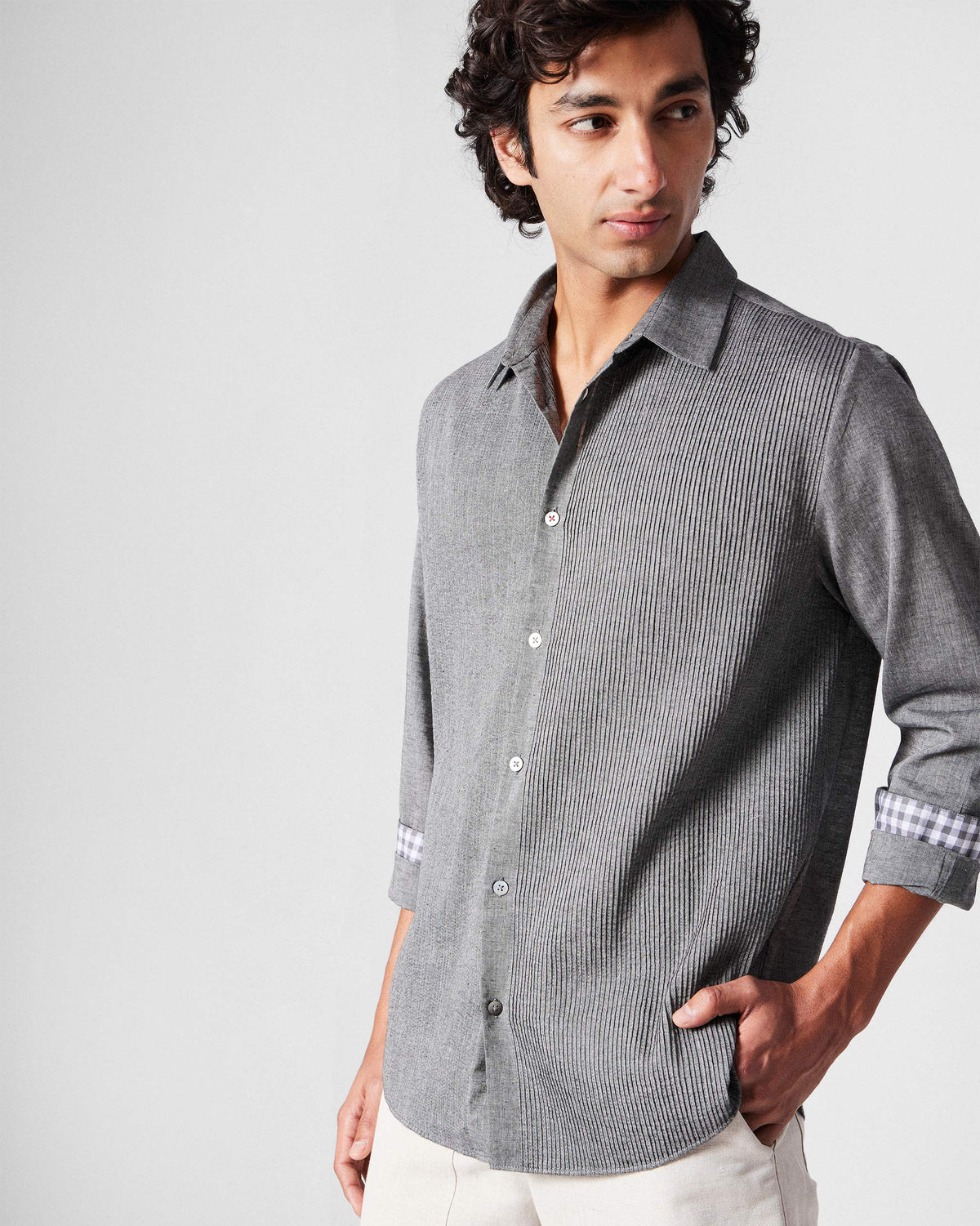 Person wearing a charcoal Nava shirt with a pintuck panel and rolled gingham-lined cuffs.