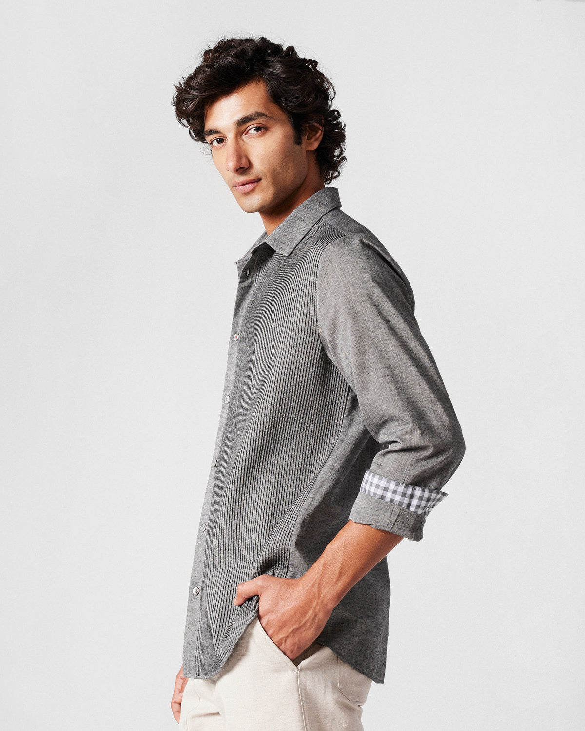 Side view of a charcoal Nava shirt with rolled sleeves and gingham cuff lining.