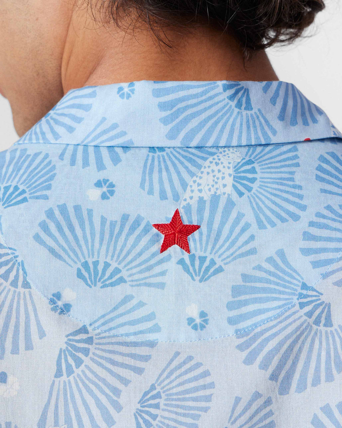 Close-up of the Mistari shirt back showing a red embroidered star on light blue print.