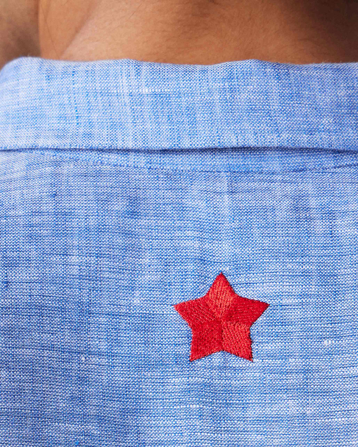 Close-up of a light blue Hakuna Shirt showing a red star at the back collar.
