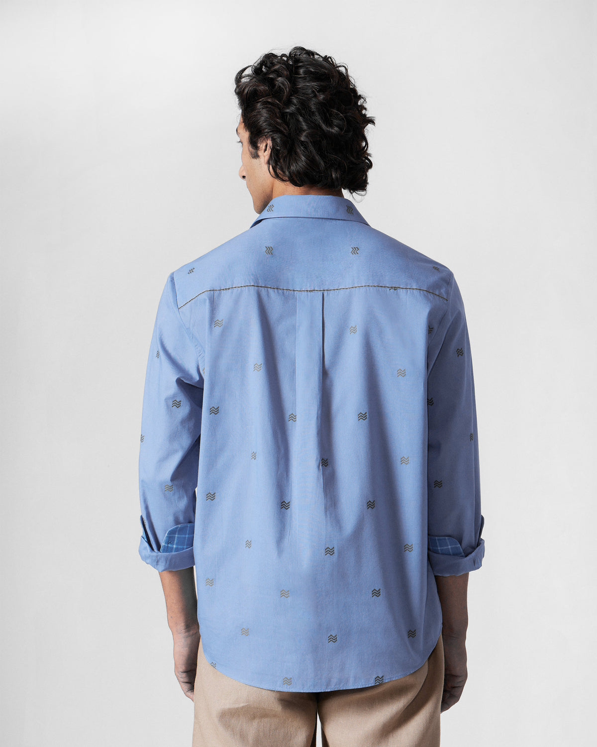 Back of a blue Sindhu Shirt with a box pleat and wavy motif print.