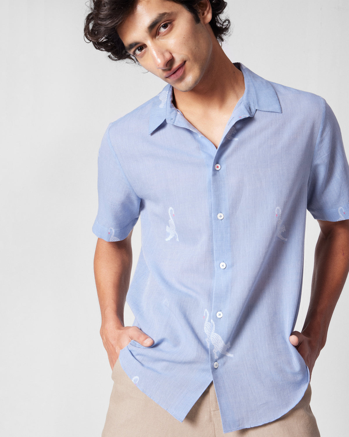 Person wearing a light blue half-sleeve shirt with white animal motifs.