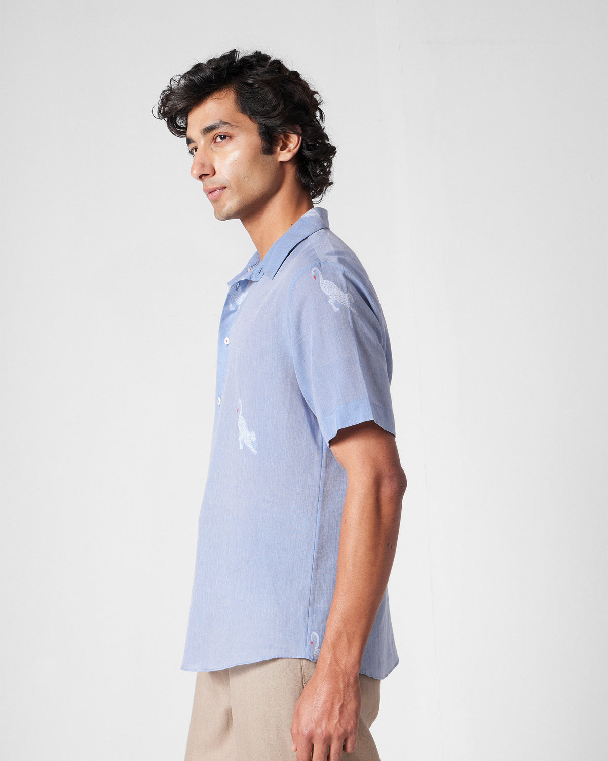 Side view of a light blue half-sleeve shirt with white animal motifs.