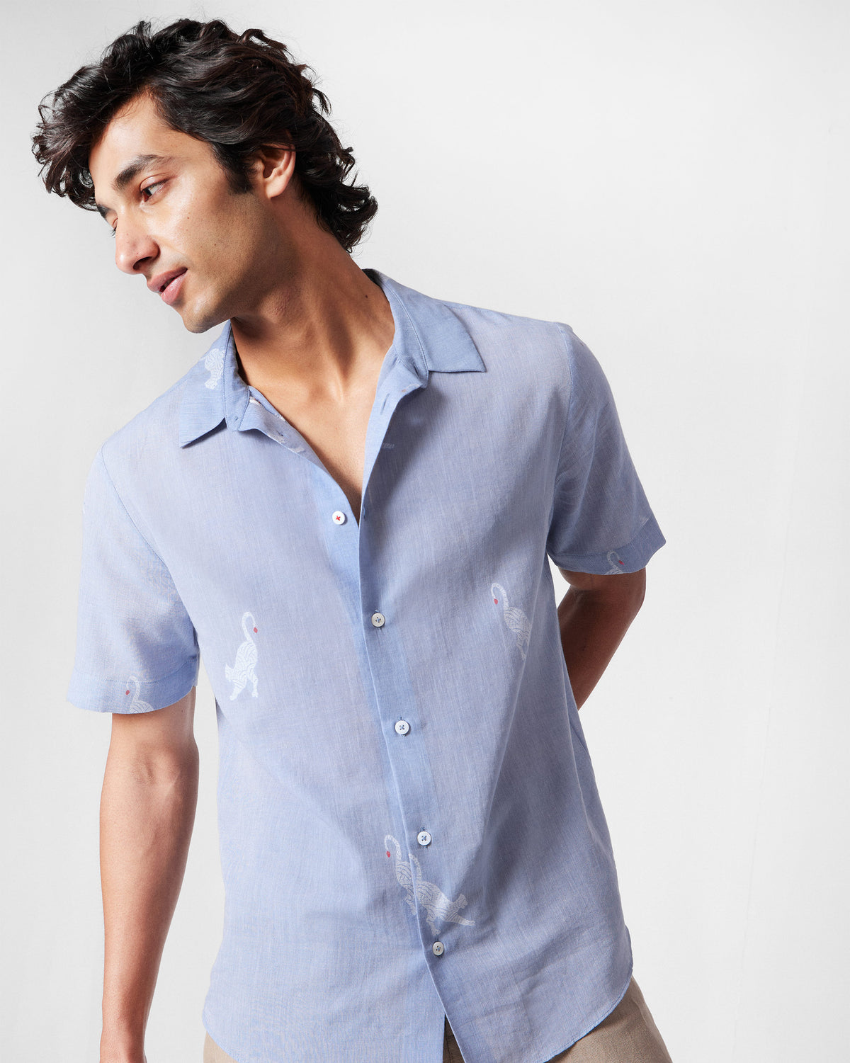 Person wearing a light blue half-sleeve shirt with white animal motifs.