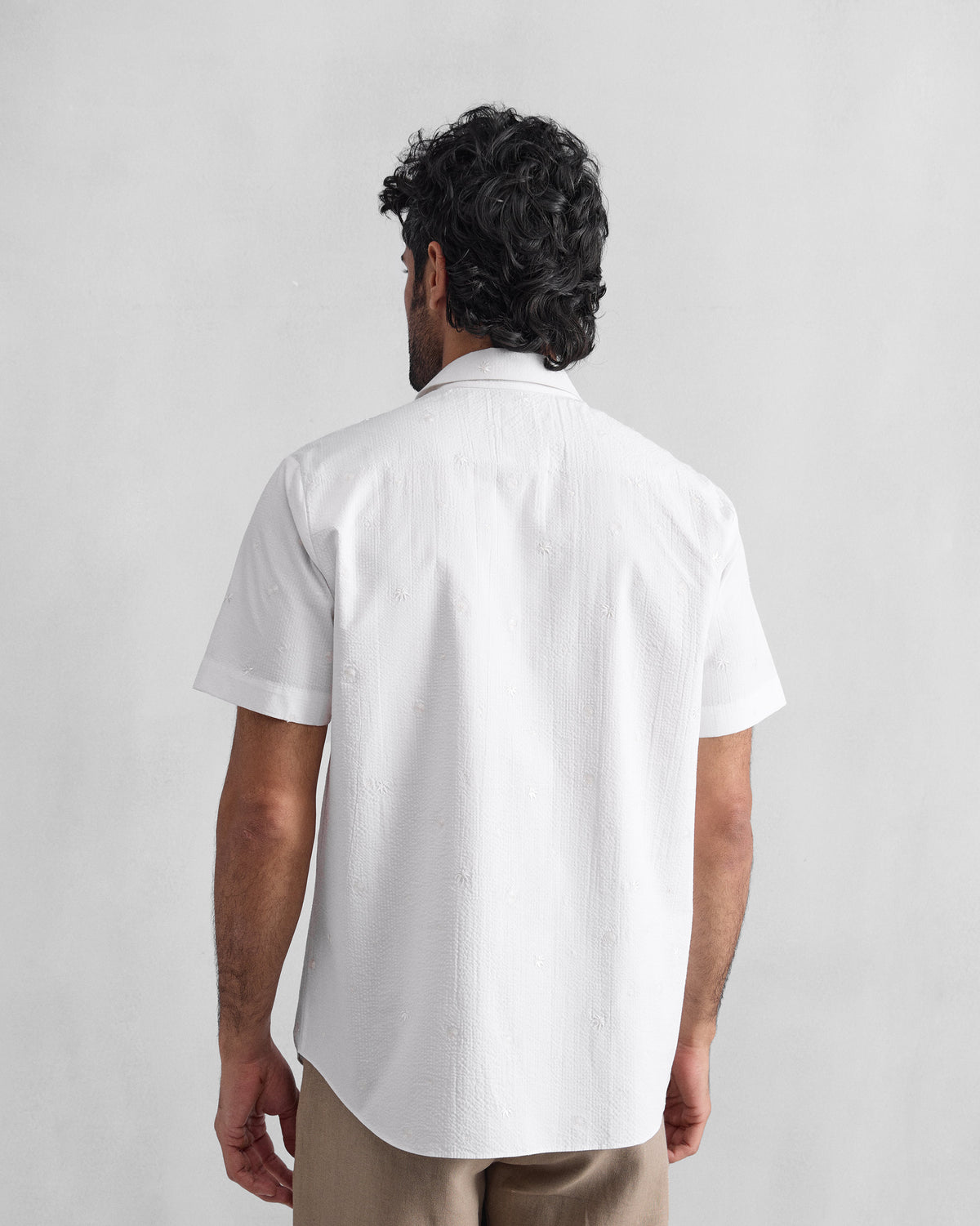 Back of a white half sleeve shirt with scattered tonal embroidery.