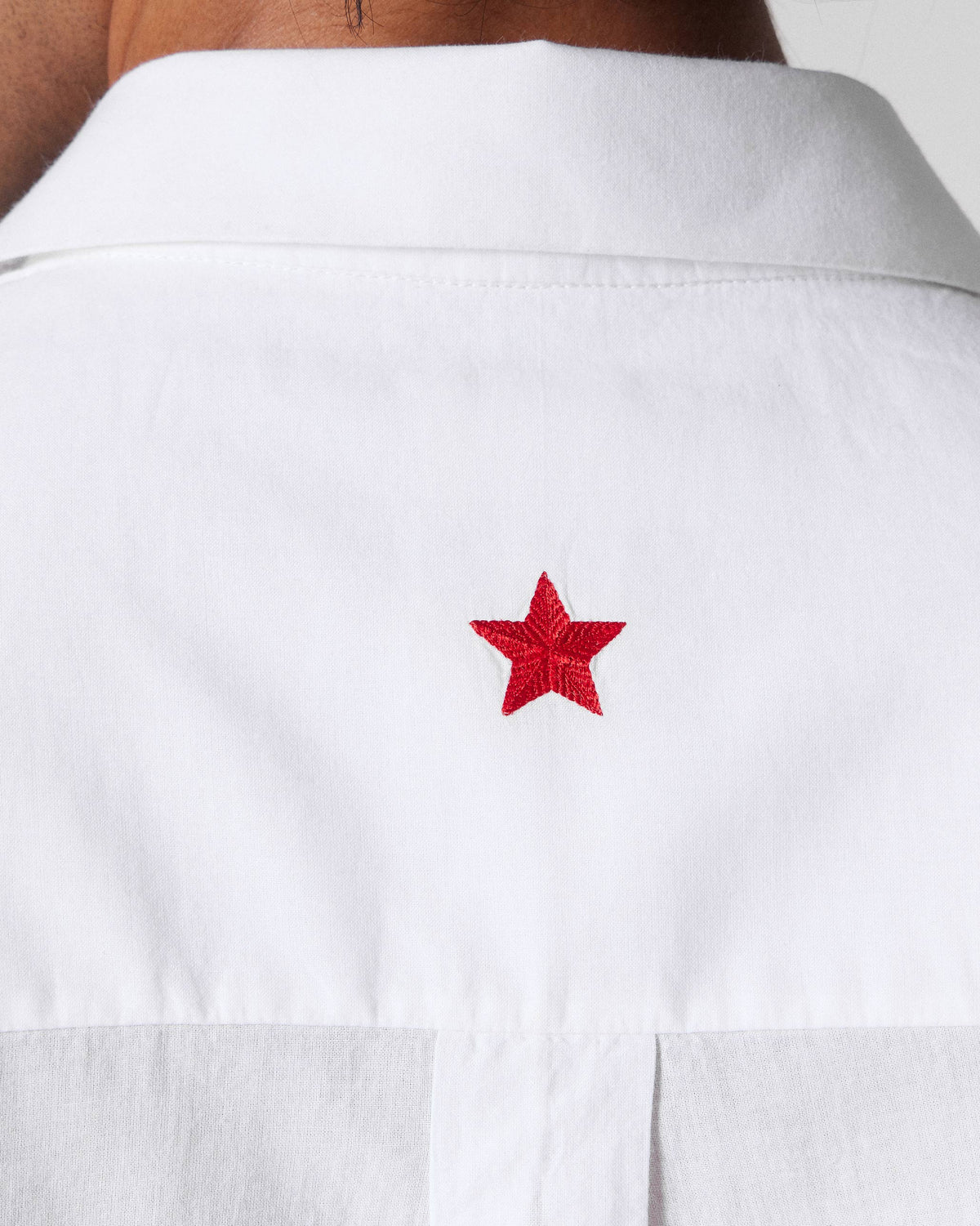 Close-up of a red star on the back of a white Basalt shirt.