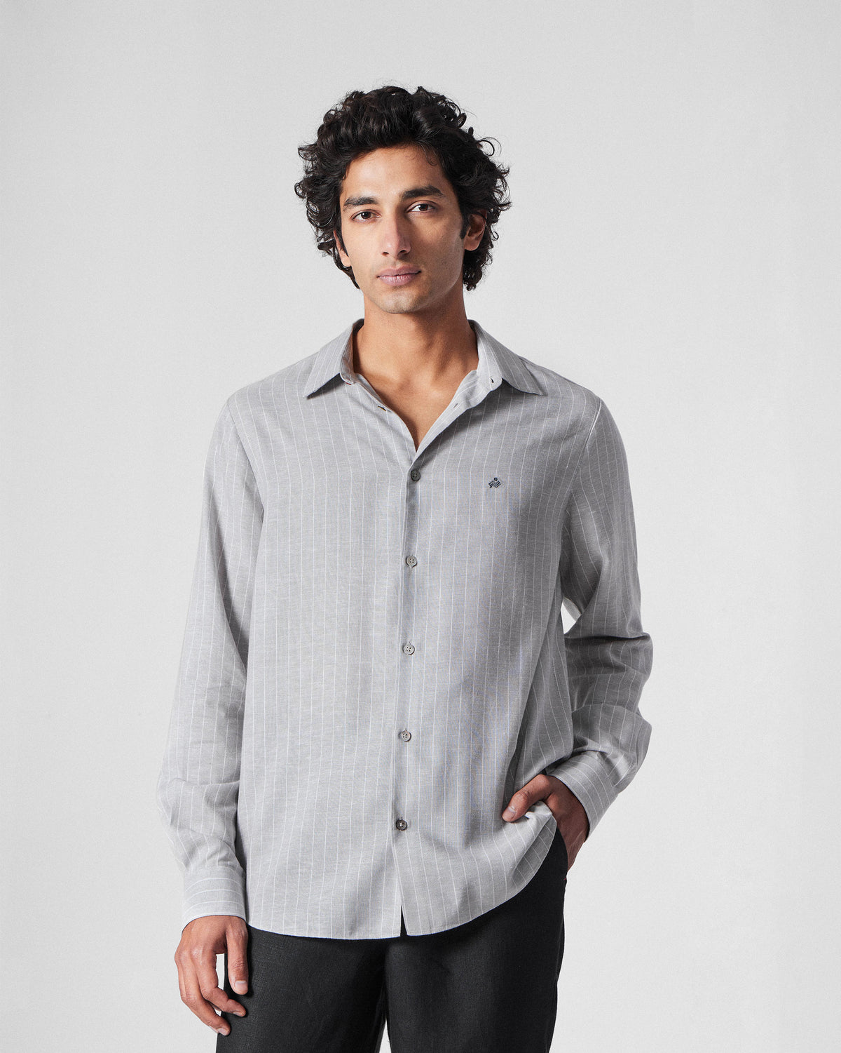 Person wearing a charcoal striped Silas Shirt with a small chest logo.