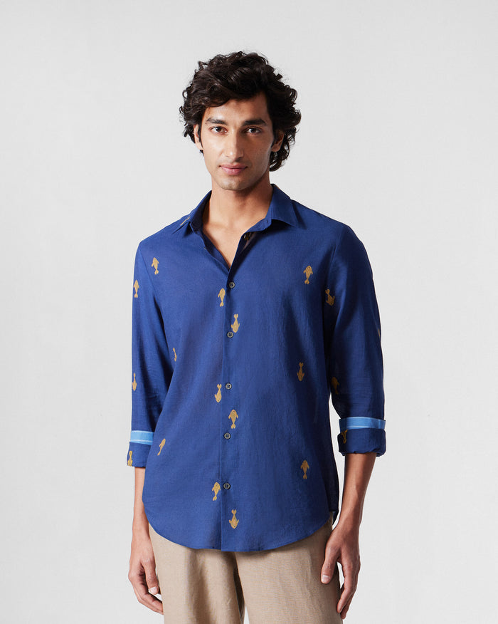 Person wearing a navy Hakuna Shirt with yellow fish motifs and contrast cuffs.