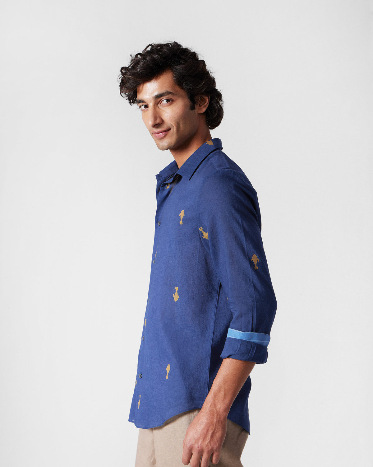 Three-quarter view of a navy Hakuna Shirt with yellow fish motifs.