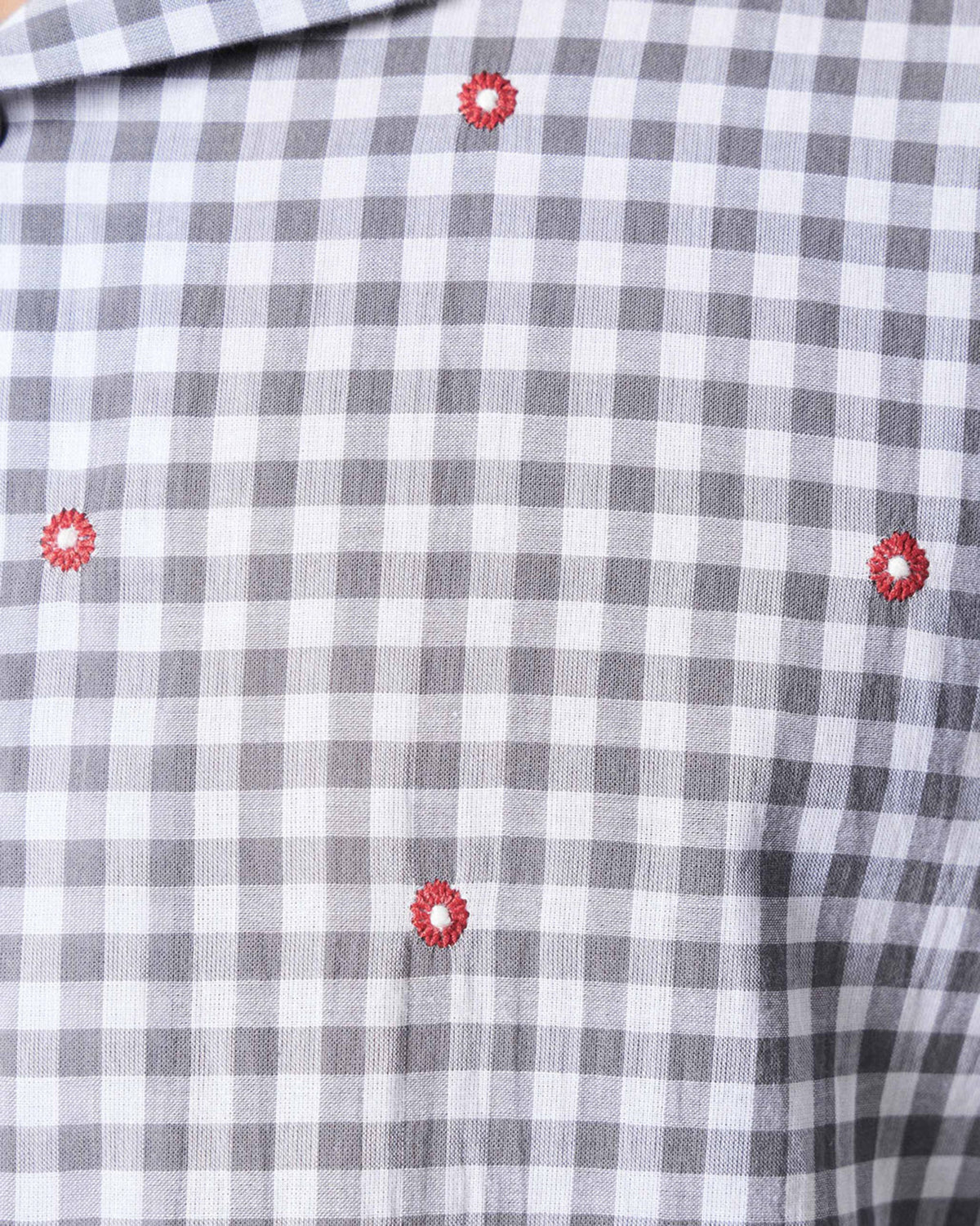 Close-up of charcoal and ivory Mistari checks with red embroidered dots.