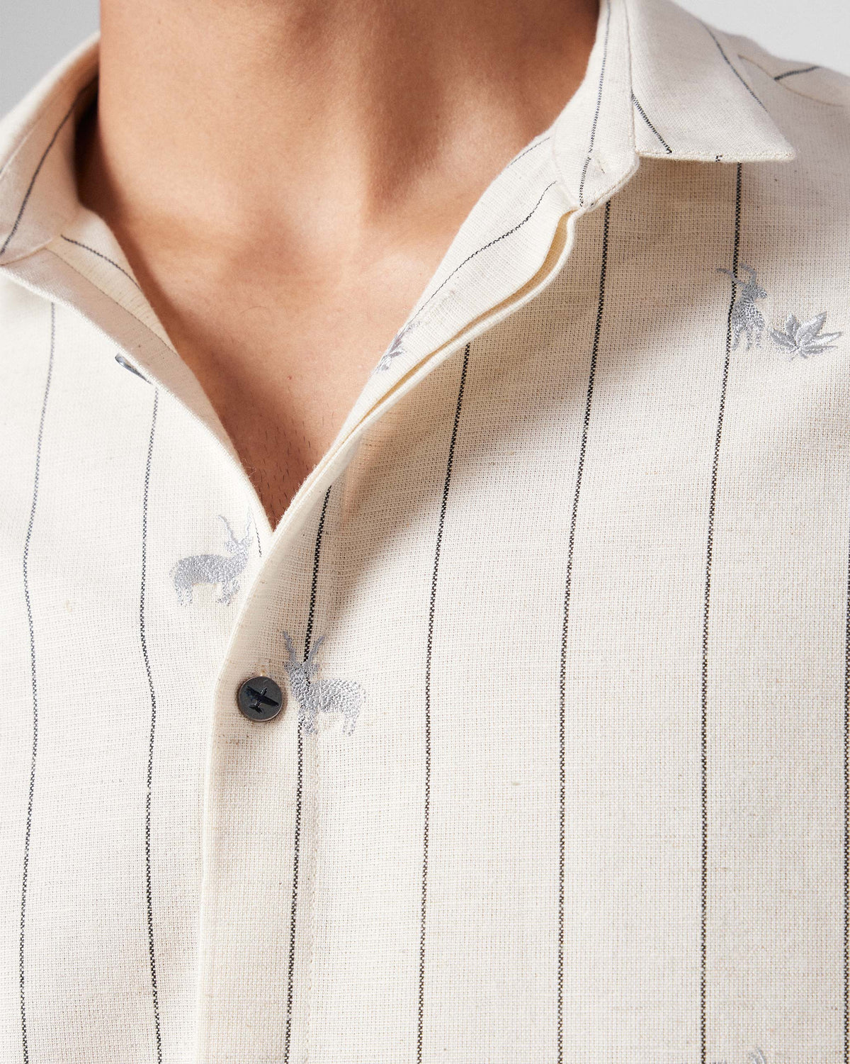 Close-up of deer and leaf embroidery on an ivory Riverine Shirt.