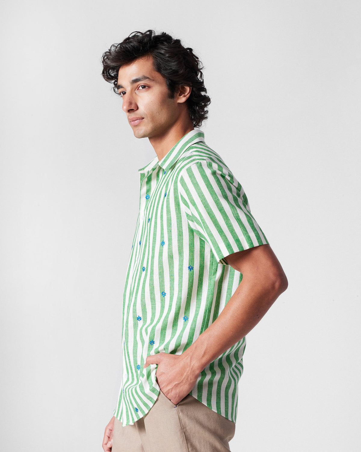 Side view of a green-and-white striped half-sleeve shirt with blue embroidery.